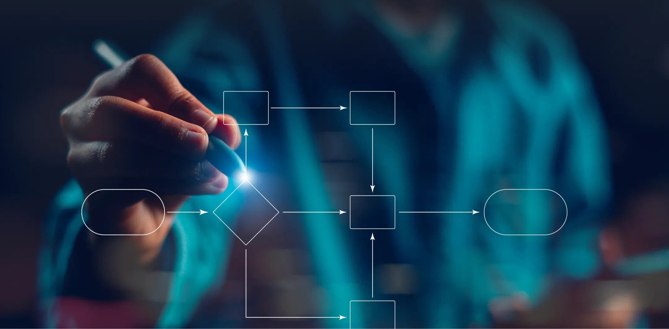 A hand holding a stylus draws a glowing digital flowchart with boxes, arrows, and a diamond shape on a transparent screen, against a blurred background of a person in a blue shirt. The focus is on the flowchart elements and the illuminated pen tip.